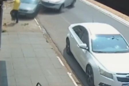 Imagem colorida de homem de camiseta amarela prestes a ser atropelado. Metrópoles