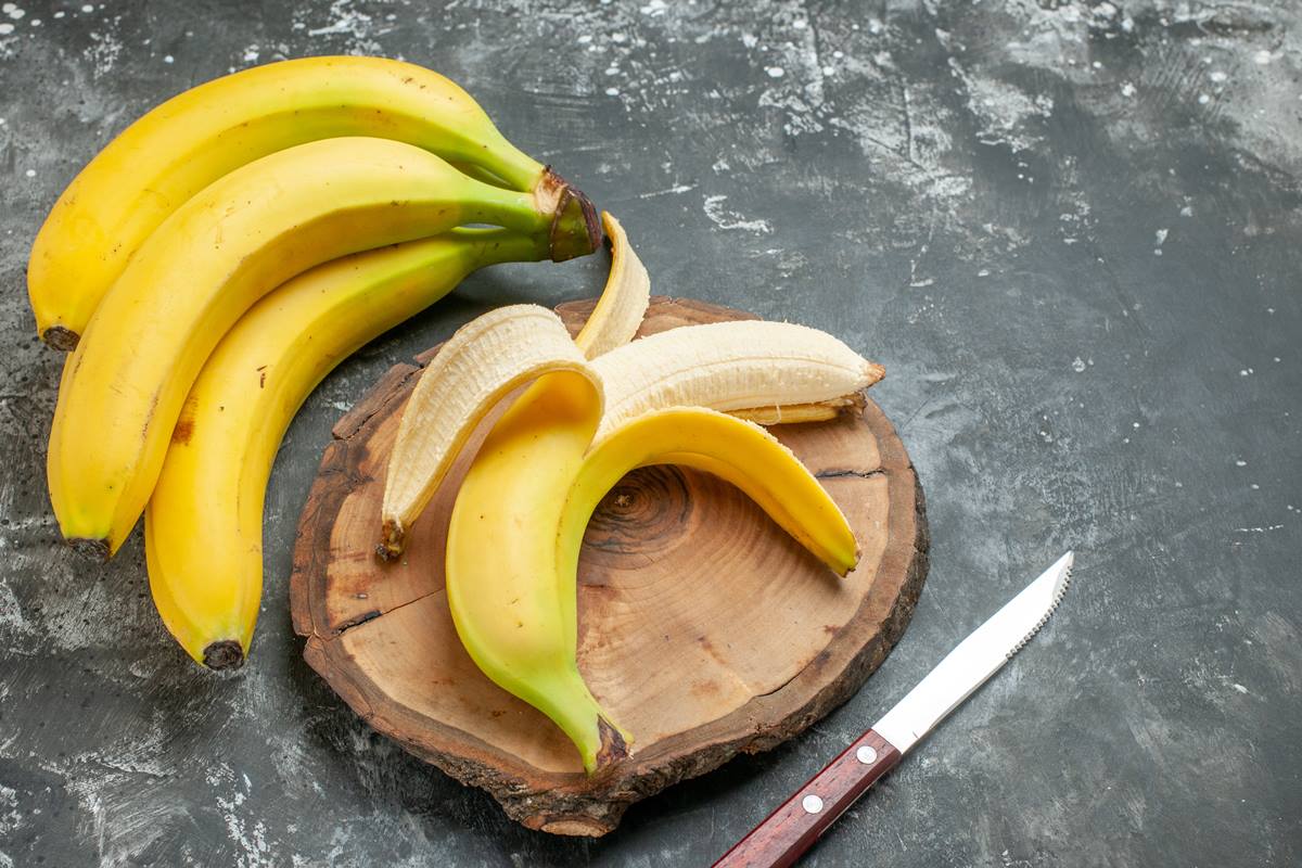 Foto colorida de penca de banana e uma fruta descascada em cima de uma tábua - Metrópoles
