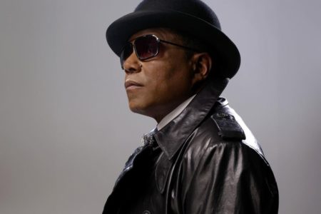 Tito Jackson, irmão de Michael Jackson, posa de chapéu e jaqueta preta - Metrópoles