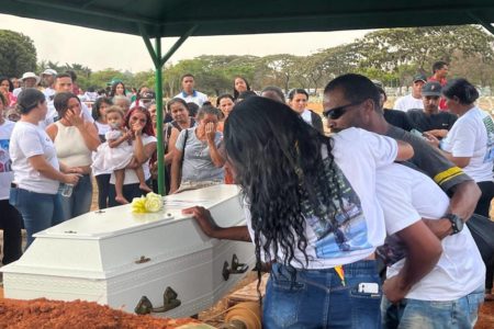Foto colorida de pessoas sepultando um caixão com criança
