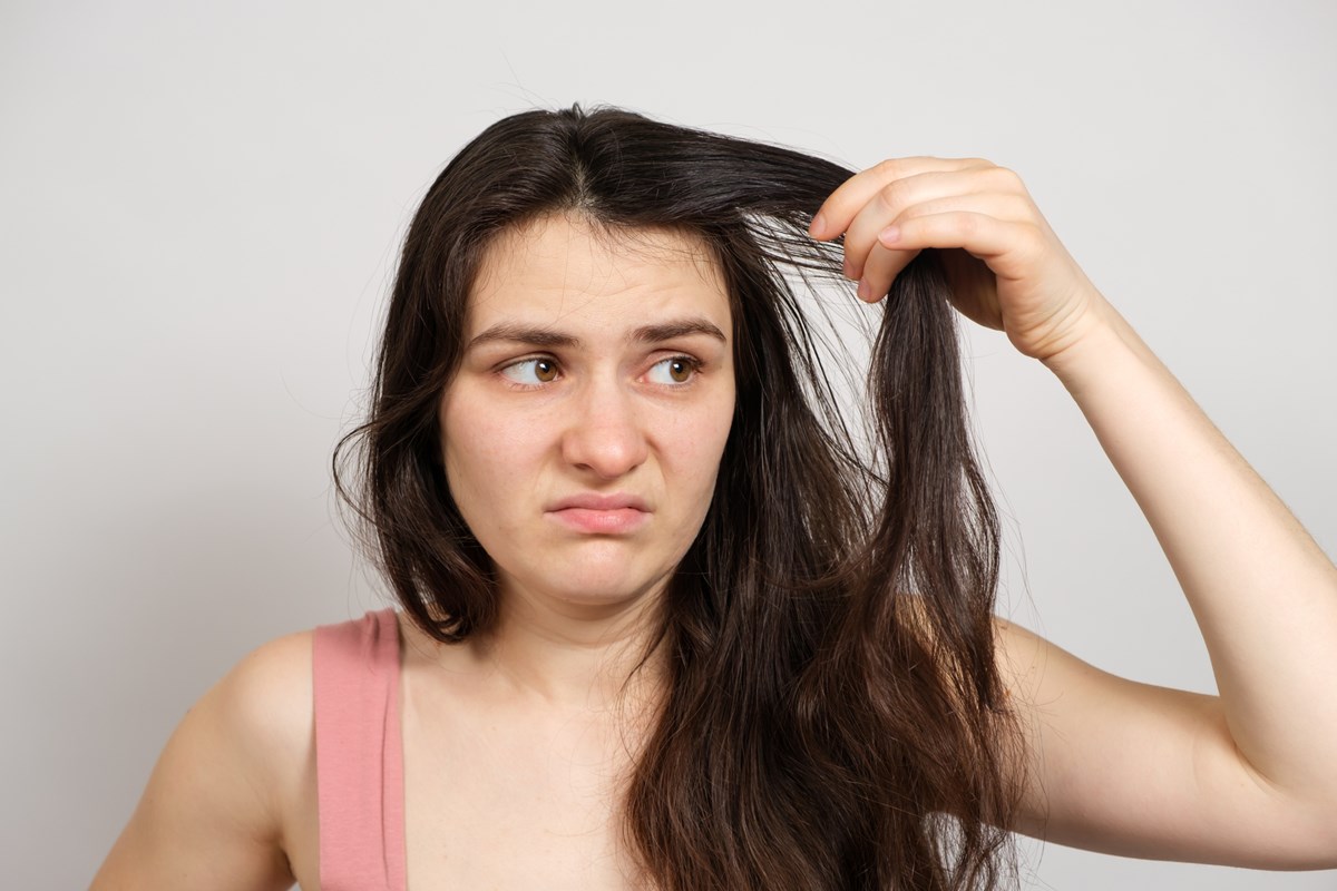 Mulher faz careta enquanto pega no próprio cabelo - Metrópoles