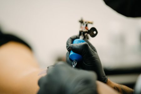 Foto colorida de uma mulher tatuando - Metrópoles