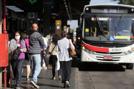 Imagem colorida de pessoas em um ponto de ônibus