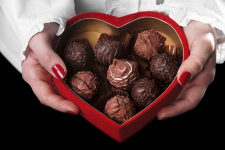 Mulher segura caixa em formato de coração com bombons de chocolate - Metrópoles