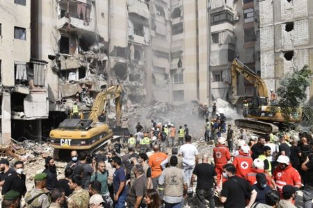 Foto colorida de oficiais usando equipamento de construção para remover destroços após o ataque aéreo do exército israelense no distrito de Dahieh, no sul de Beirute - Metrópoles