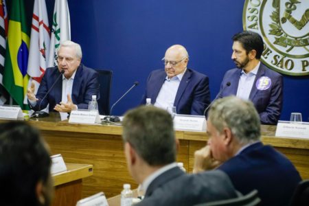 Imagem colorida mostra auditório de reuniões da associação comercial com vários homens brancos de terno sentados - Metrópoles