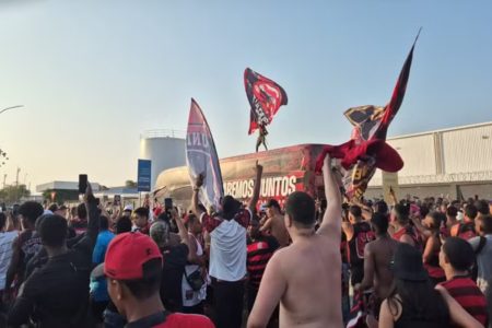 Imagem colorida da torcida do Flamengo e do ônibus do clube no Galeão