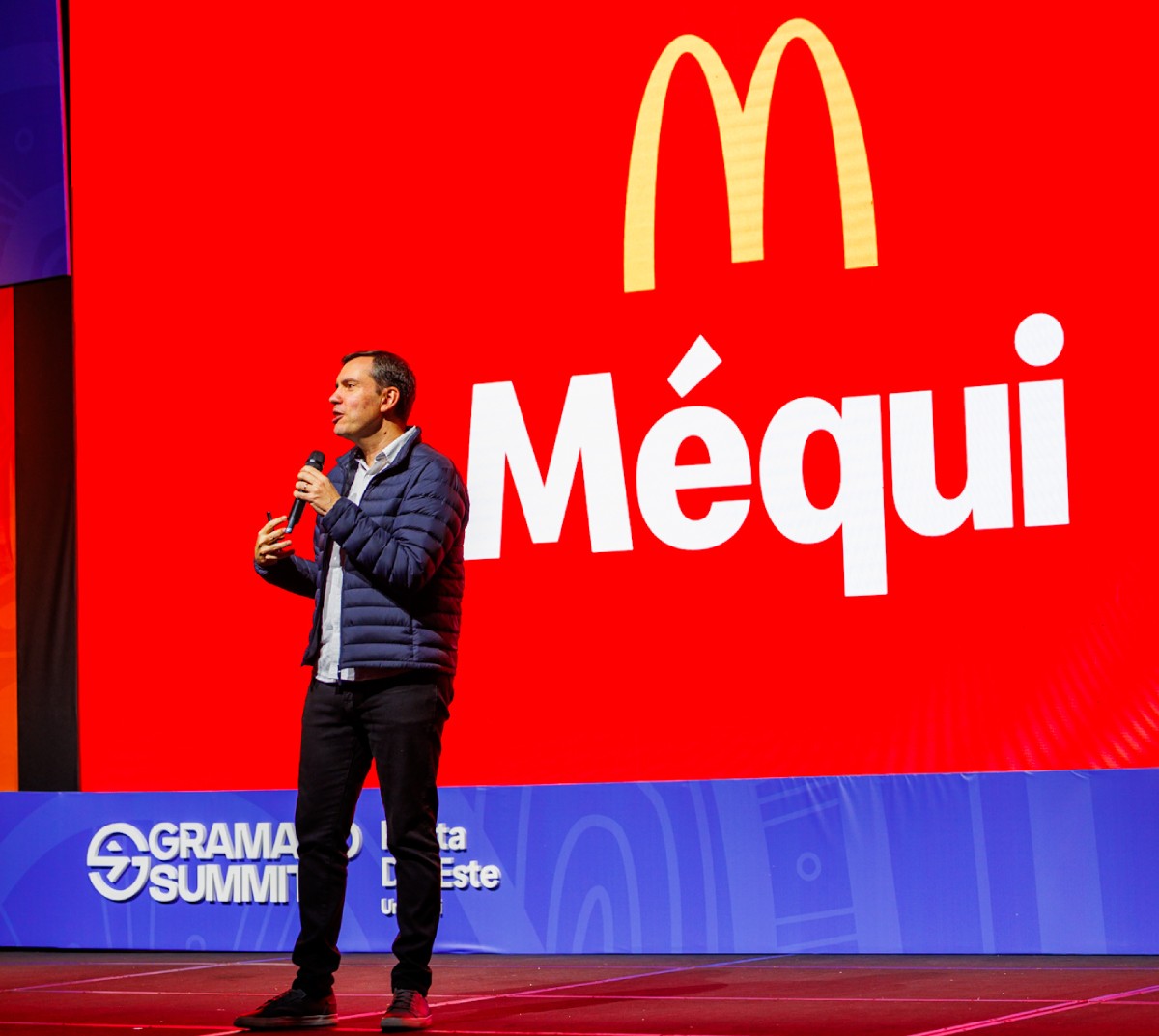 Fotografia colorida mostrando homem palestrando com a marca do McDonald's atrás em um telão-Metrópoles