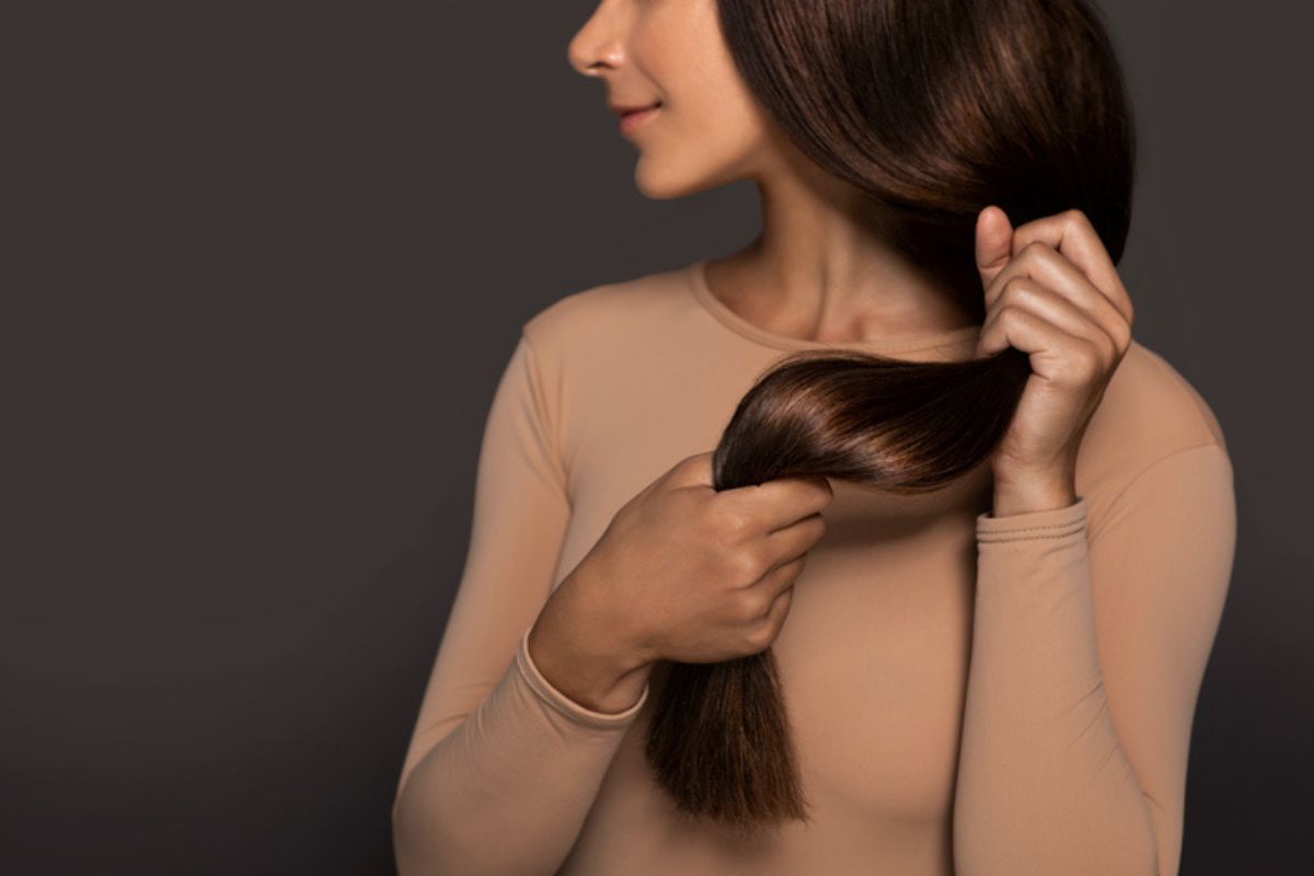 Imagem colorida de mulher segurando cabelo alisado