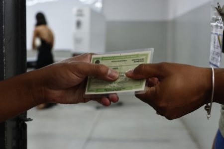 Imagem colorida de pessoas segurando título de eleitor - Metrópoles