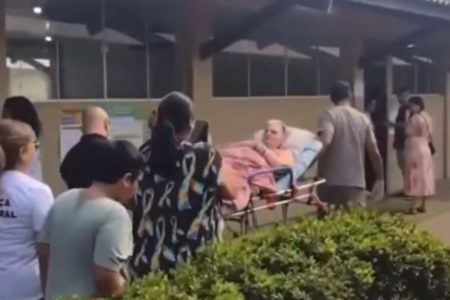 Imagem colorida de mulher de 72 anos chegando de maca em seção eleitoral - Metrópoles