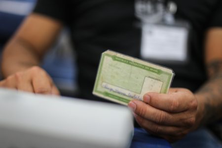 Imagem colorida com zoom aproximado de pessoa segurando título de eleitor - Metrópoles
