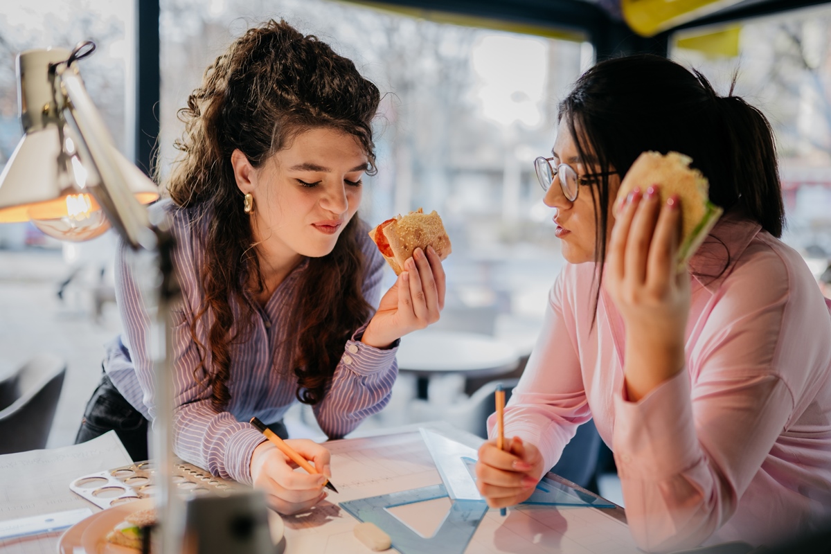 Foto colorida - duas mulheres comendo fast-food