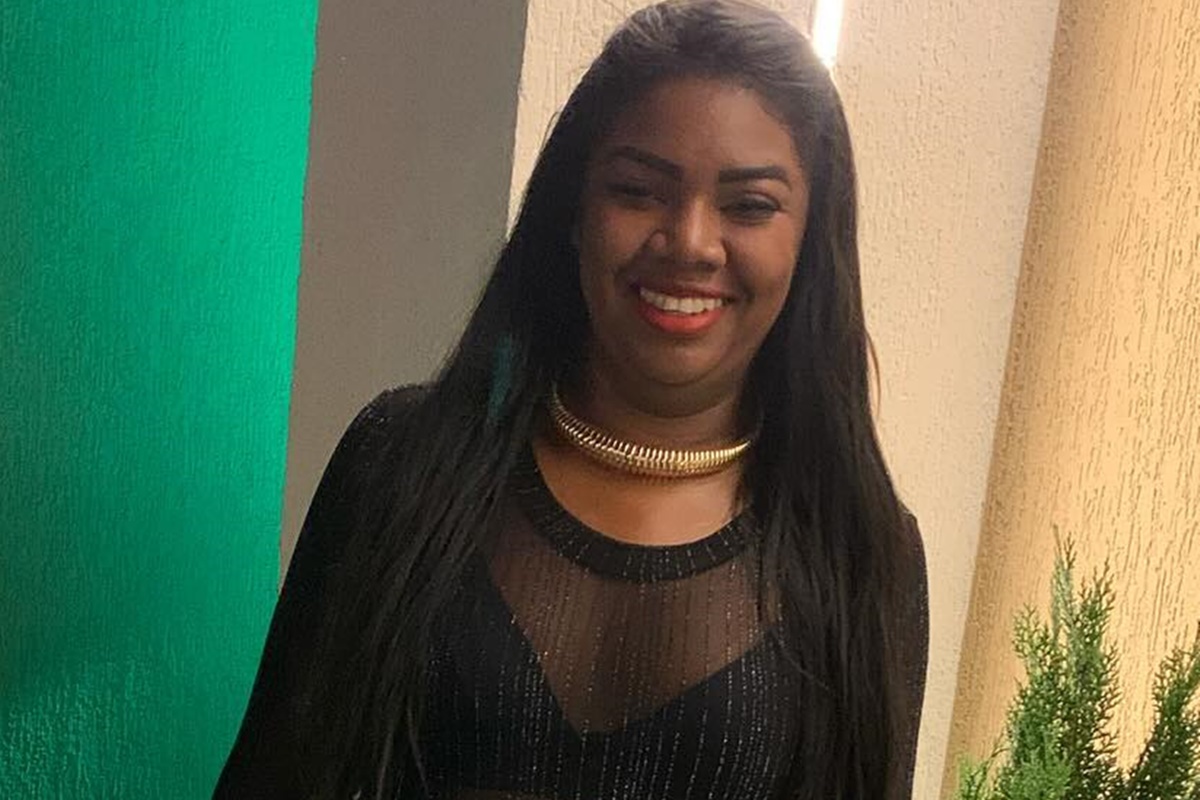 Raquel Brito posa, sorridente, de cabelos soltos e usando um look preto - Metrópoles