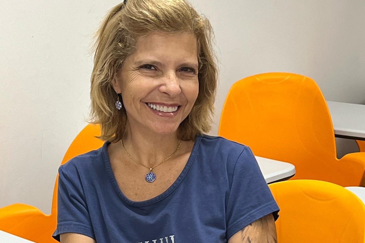 Rose Miriam, viúva de Gugu Liberato, posa sorridente com uma camisa azul - Metrópoles