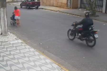 Imagem colorida de homem de moto próximo a mulher vítima de assalto. Metrópoles