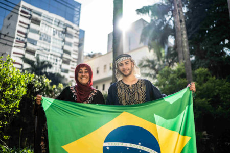Imagem colorida, duas pessoas segurando a bandeira do Brasil