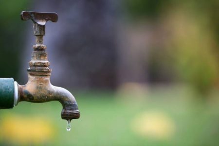 Imagem colorida de torneira com gota de água saindo - Metrópoles