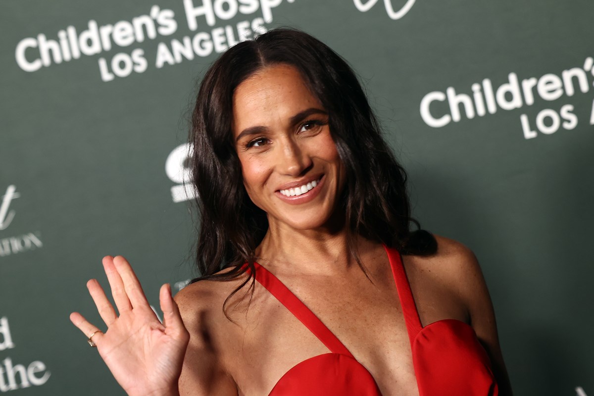 Foto colorida de mulher com vestido vermelho e acenando - Metrópoles