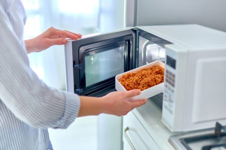 Aquecendo um recipiente de comida no moderno forno de micro-ondas - Metrópoles