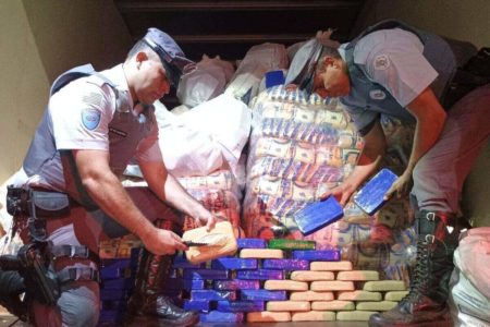 Foto colorida de tijolos de cocaína, em baú de caminhão, perto de embalagens de flocos de milho - Metrópoles