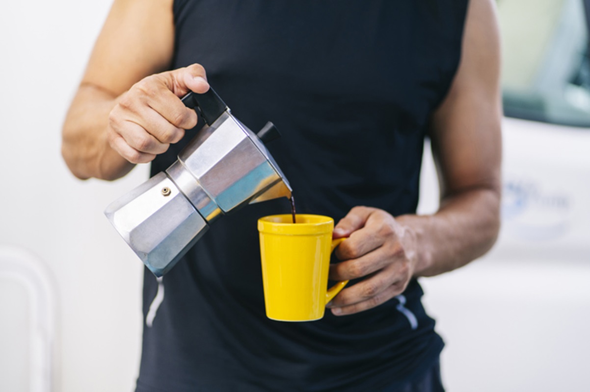 Imagem colorida de homem de camisa preta servindo xícara de café - Metrópoles