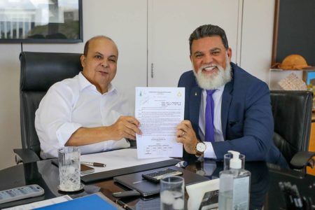 Foto colorida dois homens segurando pedaço de papel