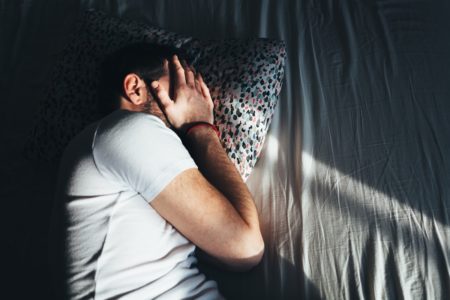 Homem deprimido deitado chorando na cama - Metrópoles