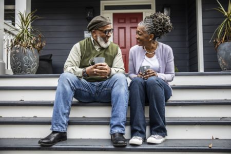 Duas pessoas idosas sentadas em escada conversando e sorrindo - Metrópoles