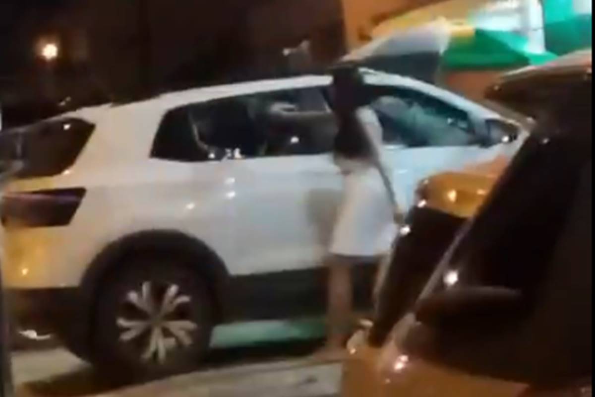 Mulher usando pedra para quebrar vidro do carro do veículo