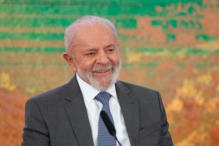 Presidente Lula sorri com fundo colorido - Metrópoles
