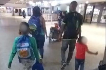Casal com duas crianças, todos de costas, caminhando - Metrópoles