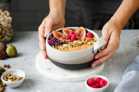 Imagem colorida de tigela com frutas nas mãos de pessoa