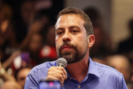 Imagem colorida mostra Guilherme Boulos discursando com microfone na mão - Metrópoles