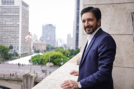 Imagem colorida mostra o prefeito Ricardo Nunes, homem branco, de cabelo e barba pretos, vestindo terno azul e camisa branca, durante entrevista ao Metrópoles em seu gabinete - Metrópoles