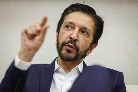 Imagem colorida mostra o prefeito Ricardo Nunes, homem branco, de cabelo e barba pretos, vestindo terno azul e camisa branca, durante entrevista ao Metrópoles em seu gabinete - Metrópoles