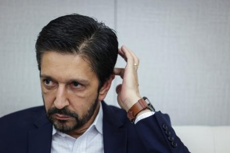 Imagem colorida mostra o prefeito Ricardo Nunes, homem branco, de cabelo e barba pretos, vestindo terno azul e camisa branca, durante entrevista ao Metrópoles em seu gabinete - Metrópoles