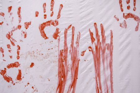 Foto colorida de mãos com tinta vermelha - Metrópoles