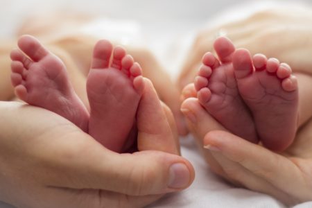 Foto mostra pai e mãe segurando os pés de bebês gêmeos. Bebês trocados, bebês gêmeos, trocados na maternidade, trocadas ao nascer
