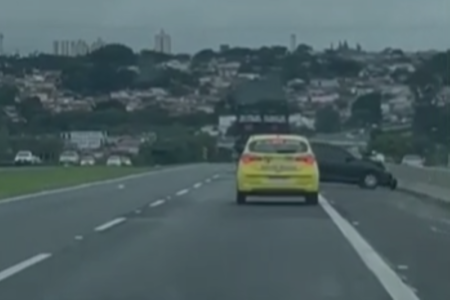Imagem colorida de carro preto batendo em mureta. Um homem estava no capô do carro, dirigido por uma mulher, sua ex, acabou arremessado em rodovia - Metrópoles