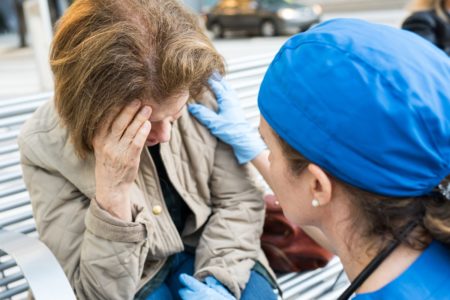 Médica ajudando uma mulher idosa na rua. Dor de cabeça, exaqueca, AVC, derrame