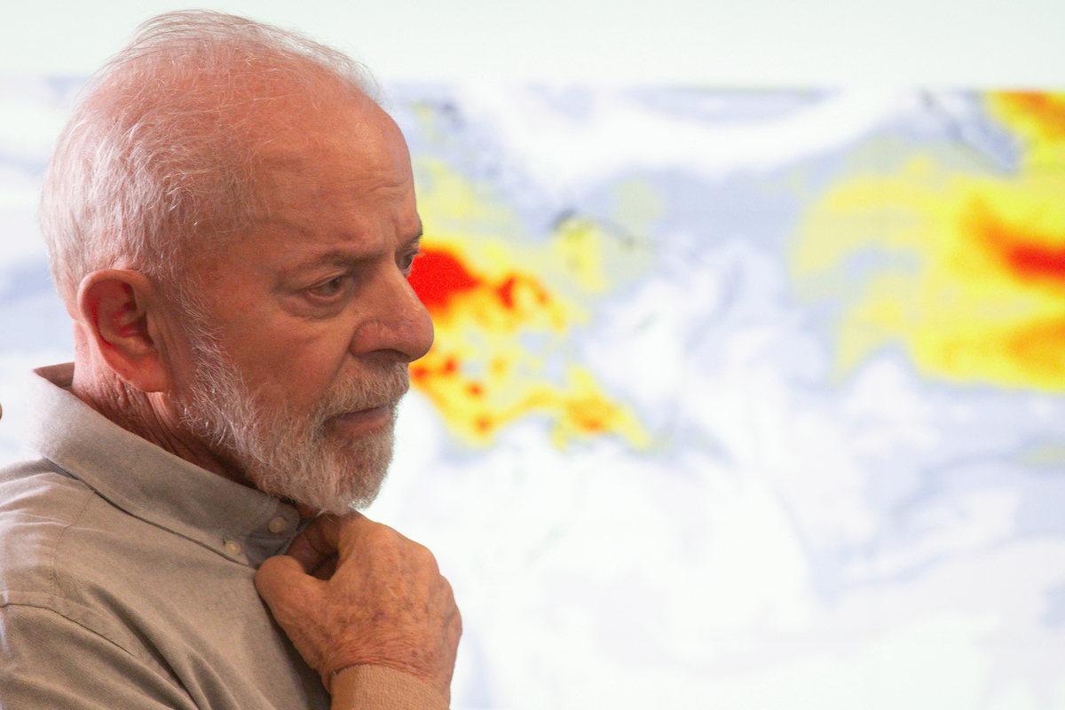 Imagem colorida do presidente Lula de perfil com mapa de queimadas atrás - Metrópoles