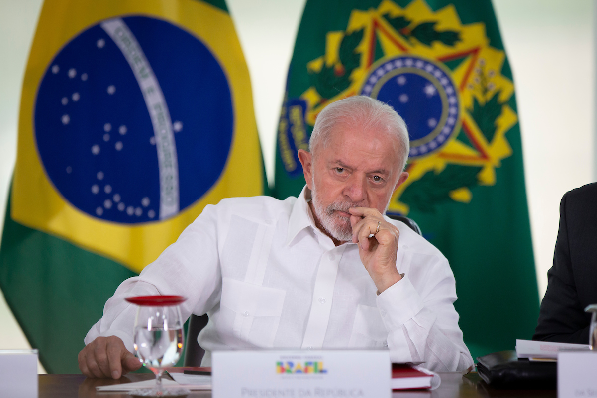 Imagem colorida de Lula com mão no rosto - Metrópoles