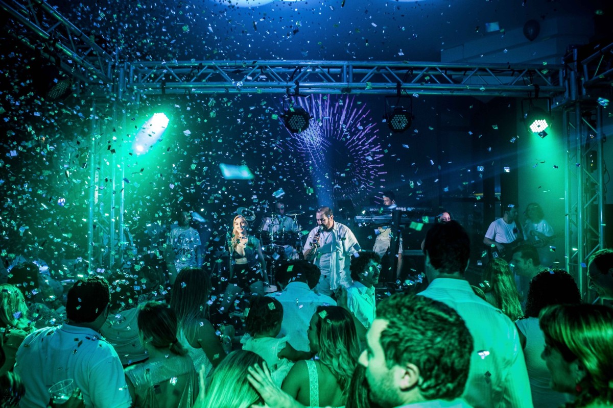 Fotografia colorida mostrando pessoas comemorando em salão de festas-Metrópoles