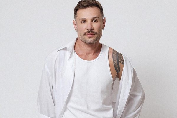 Alex Gallete posa sério e de look branco para as redes sociais - Metrópoles