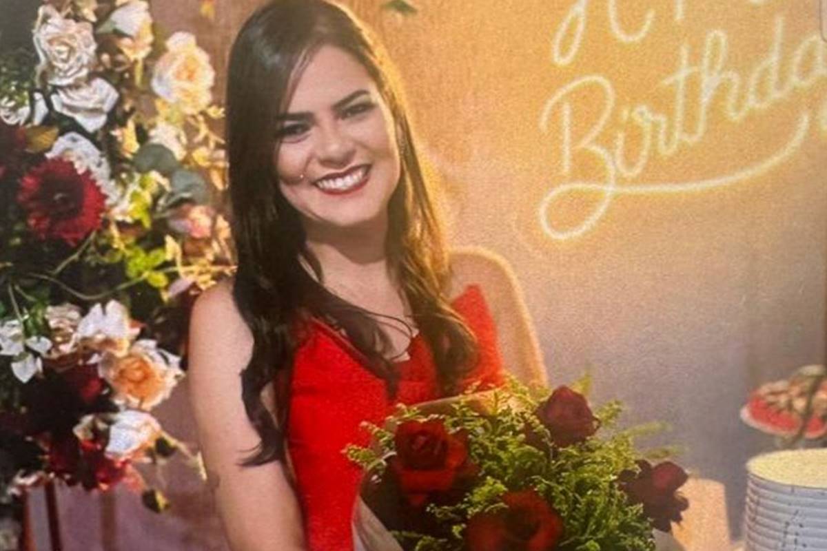 Mulher sorrindo, de vestido vermelho, segura buquê de rosas vermelhas - Metrópoles