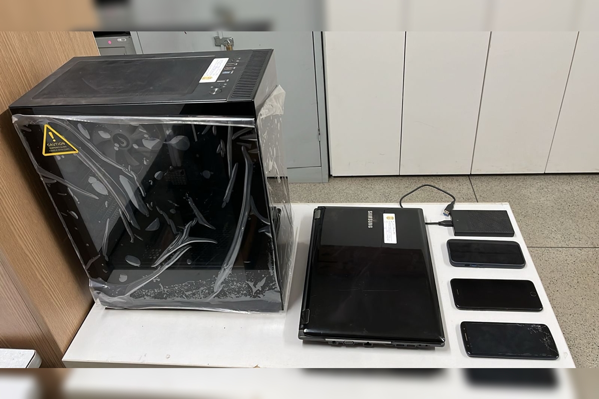 Imagem de um computador, um notebook, um HD externo e três celulares, todos pretos, sobre uma mesa branca