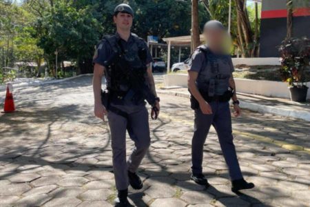 Dois PMs fardados, com boinas, caminham em área aberta, sob a luz do sol - Metrópoles