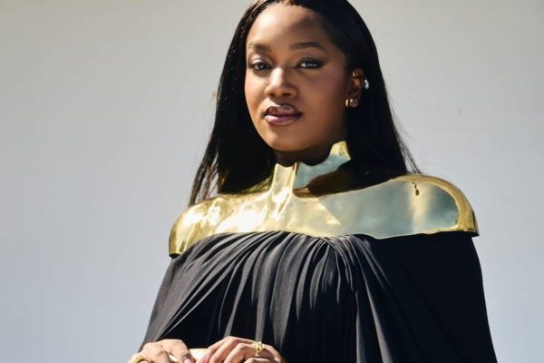 Na foto colorida, cantora IZA aparece com roupa preta e ombreira dourada, durante premiação do Grammy Latino 2024 - Metrópoles