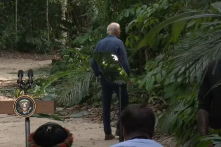 Imagem colorida do presidente Joe Biden entrando na mata